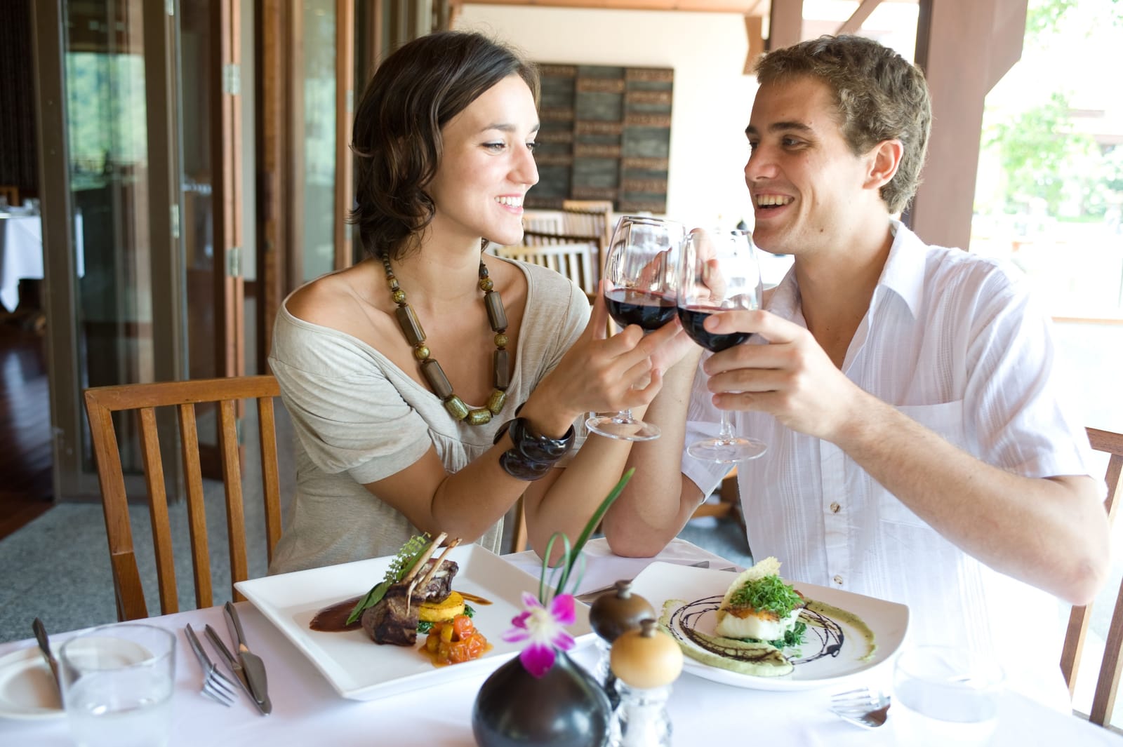 Ein Paar stößt beim Essen im Restaurant mit Rotwein an